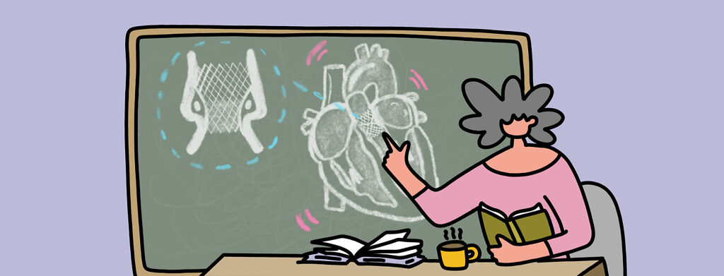 A woman sitting behind a teacher's desk, pointing to the chalkboard behind her which shows a drawing of an anatomical Heart with aortic valve replacement.